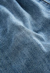 Svijetloplavi denimski materijal s teksturiranom površinom, srednje težine, s suptilnim varijacijama u boji i dubini.