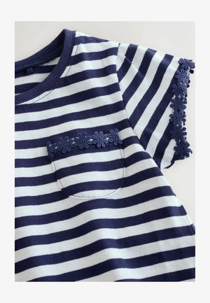 Maglietta in cotone a righe blu navy e bianche con rifiniture blu navy a fantasia floreale sulle maniche e una piccola tasca decorata con fiori simili.