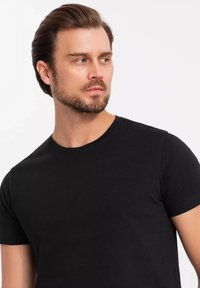 Czarna koszulka z krótkim rękawem wykonana z bawełny, z okrągłym dekoltem i dopasowanym krojem, o gładkiej fakturze i bez widocznych wzorów.