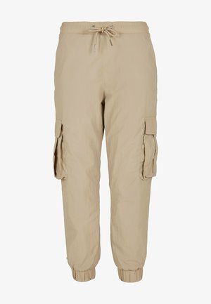 Beżowe spodnie cargo z elastycznym paskiem w talii, ściągaczami przy nogawkach, kieszeniami bocznymi i lekkim, teksturowanym materiałem. Noszone z czarnymi trampkami.