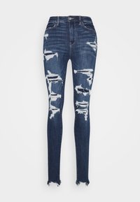 Smala jeans i mörkblå denim, med slitna hål vid knäna, fransade fållar och klassisk femficksdesign med knäppning.