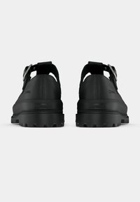 Μαύρα παπούτσια με χοντρή σόλα και ματ φινίρισμα, με ρυθμιζόμενο λουρί και υφή στην πλάτη. Η εξωτερική σόλα έχει προεξοχές για καλύτερη πρόσφυση.