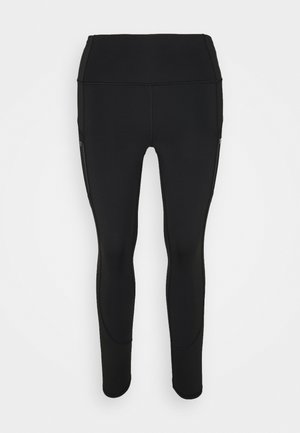 Leggings actives noirs fabriqués à partir d'un tissu lisse et extensible, avec une taille haute et des zippers latéraux discrets pour les poches.