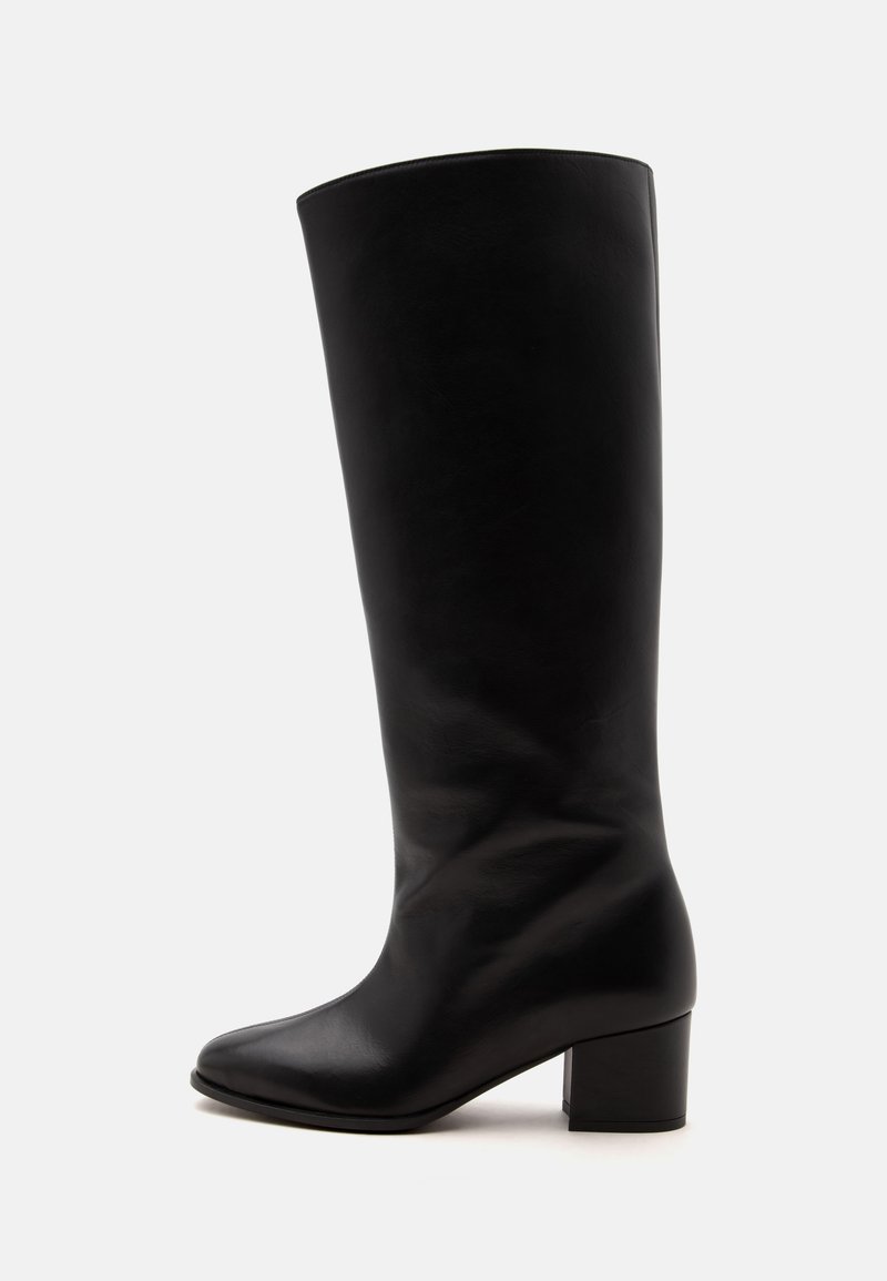Botte en cuir noire haute jusqu'au genou avec un bout arrondi et un petit talon bloc, vue de côté extérieur sur un fond uni.