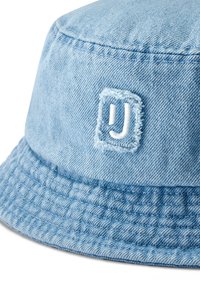 Ljusblå denim bucket cap med en texturerad skärm, sydda detaljer och en broderad logotyp på framsidan.