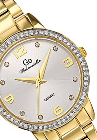 Montre en quartz couleur or avec un cadran argenté, accents en cristal, grands chiffres aux positions 12 et 3, et un bracelet à maillons métalliques.
