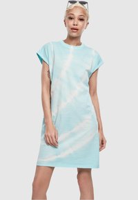 Svijetlo plava haljina s tie-dye uzorkom, kratkih rukava, opuštenog kroja, izrađena od mekog materijala. Ima bijeli vrtložni uzorak i blago zavrnute rukave.