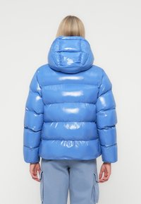 Blauwe pufferjack met een glanzende afwerking, voorzien van een capuchon en horizontale gestikte secties, cropped lengte en elastische manchetten.