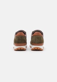 Ein Paar olivgrüne und braune Sneakers, von hinten betrachtet, mit weißen Zwischensohlen und Außensohlen aus Gummi auf einem weißen Hintergrund.