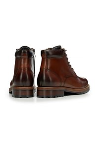 Brązowe skórzane botki za kostkę o gładkim wykończeniu, zaokrąglonym nosku i wiązane z przodu. Charakteryzują się kontrastowym ciemnym obcasem i trwałą gumową podeszwą.