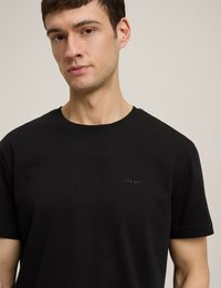 Czarny bawełniany t-shirt z krótkim rękawem, z subtelnie wyhaftowanym logo na klatce piersiowej. Gładka tekstura i klasyczny okrągły dekolt.