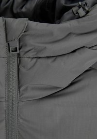 Grey jacket with a zip closure, featuring a sleek design, textured fabric, and a high collar. Includes adjustable hardware for fit.