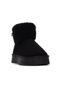 Botín negro de ante con un cuello de pelaje. Presenta una suela de plataforma corta y una suela exterior de goma negra texturizada.