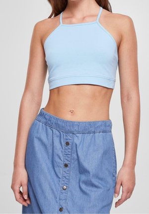Cropped top azzurro chiaro in tessuto morbido, abbinato a una gonna di jeans con vita elastica e bottoni in metallo.