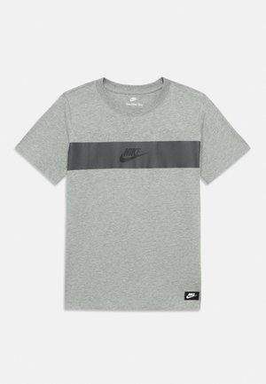 Сива тениска с къси ръкави на Nike с черна хоризонтална ивица през гърдите и логото на Nike в центъра и долния ъгъл.