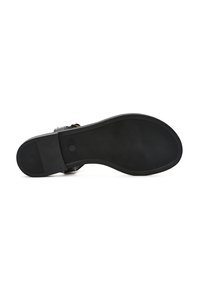 Suola di sandalo nera con superficie texture, dotata di tacco piatto e punta arrotondata. Hardware minimal con finitura liscia e dettagli sottili.