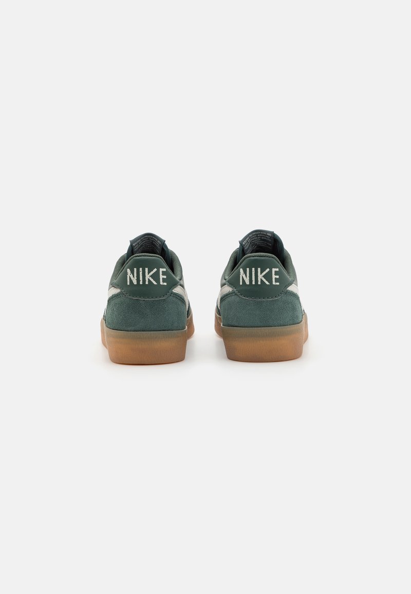 Las zapatillas Nike presentan una parte superior de ante verde, suela de goma y una marca blanca en el talón. El diseño incluye un collar acolchado y acentos en contraste.