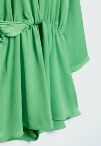 Vestido verde con una tela suave y texturizada. Presenta una cintura elástica y un dobladillo fluido, mostrando una silueta suave.