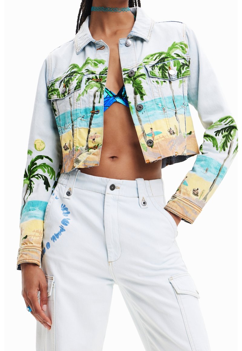 Kort ljus denimjacka och byxor med färgglada tropiska strand- och palmtryck, bärs över en blå mönstrad bikinitopp.