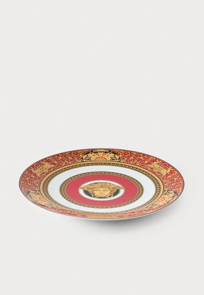 Decorative plate featuring a red and gold border, white center, and intricate patterns. Central image displays a stylized face.