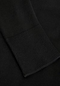 El tejido de punto negro presenta un puño acanalado con una textura suave. El material es suave y de tejido denso, con un color sólido y sin patrones.