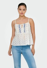 Top peplum blanco con tirantes ajustables, tejido texturizado, bordado floral azul en el centro y detalle de lazo en el escote.