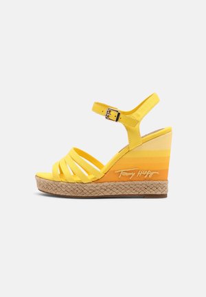 Yellow wedge sandals with multiple straps, a buckle closure, and an espadrille-style sole featuring a gradient orange texture.