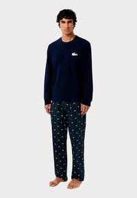 Námořnická košile s dlouhým rukávem a bílým logem; vzorované pyžamové kalhoty se zelenými pruhy a malými bílými logy; bavlněný materiál, volný střih.