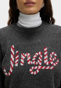 Grauer Pullover mit einem "Jingle"-Design aus rot-weißen gestreiften Pailletten. Mit Stehkragen und einem weichen, strukturierten Stofffinish.
