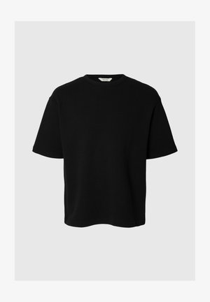 T-shirt noir à manches courtes et col rond avec une coupe décontractée et une texture de tissu visible sur un fond gris clair.