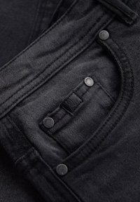 Tissu en denim noir avec une poche avant dotée de quincaillerie argentée et d'un patch avec logo. La texture est lisse avec des détails de couture subtils.