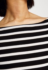 Tessuto a strisce bianche e nere con una texture morbida, caratterizzato da ampie strisce orizzontali e un collo off-the-shoulder.