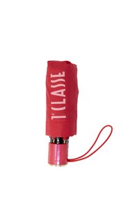 Ombrello rosso con un manico lucido rosso e oro. La copertura è piegata e presenta il testo "1 CLASSE" in bianco. Include un cinturino rosso da polso.