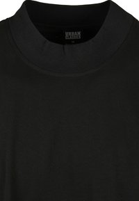 T-shirt en coton noir avec un col haut et un col en côte. Design simple, texture douce, sans motifs visibles ni accessoires.