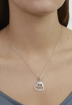 Collier pendentif en forme de cœur en argent avec une pierre centrale en zirconium cubique, entourée de petites pierres, suspendu à une chaîne délicate.