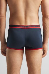 Námořnické pánské boxerky s červeným páskem, s těsným střihem a hladkou texturou. Název značky je viditelný na pásku.