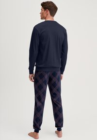 Marineblauwe longsleeve top met ronde hals; geblokte pyjamabroek in marineblauw met rode en witte accenten; zacht materiaal; comfortabele pasvorm.