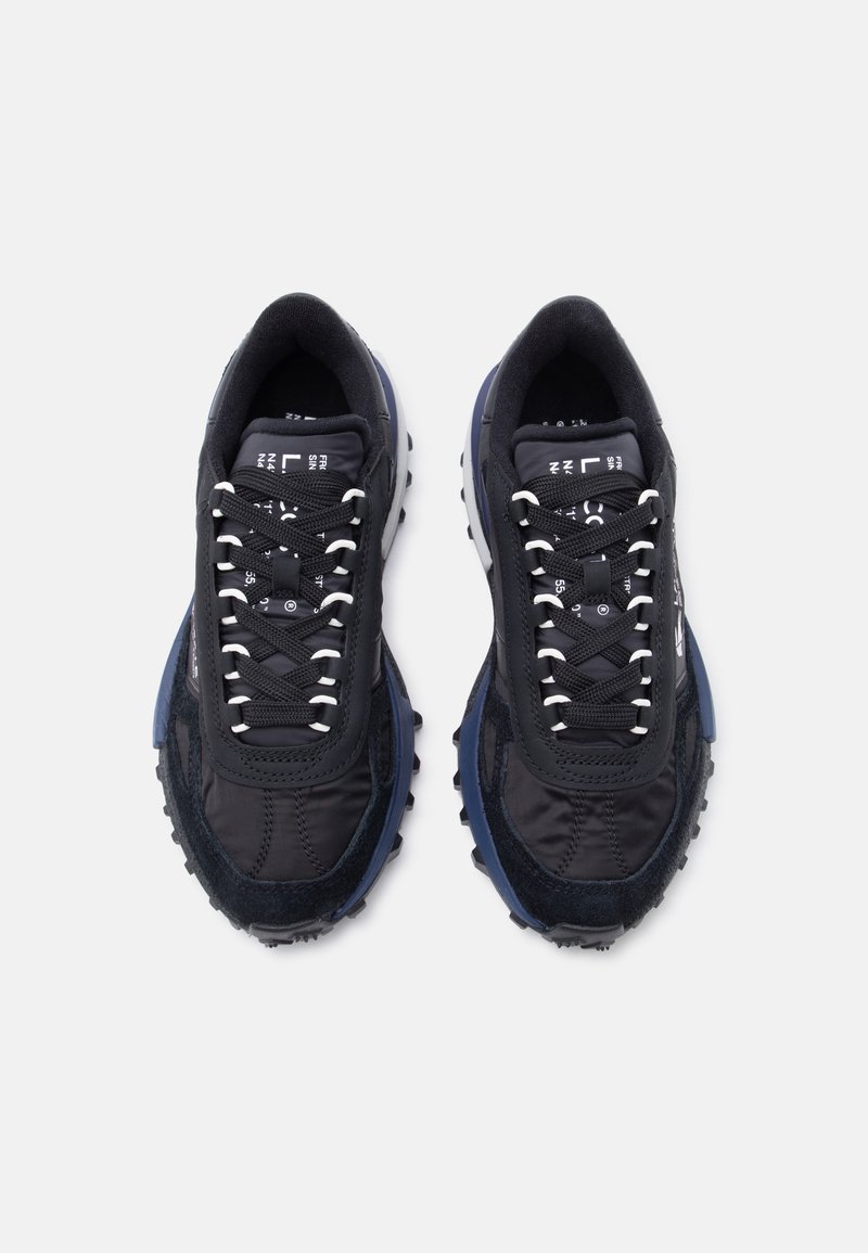 Coppia di scarpe da ginnastica nere e blu navy con passanti per lacci bianchi, suole testurizzate e testo stampato sulla linguetta, viste dall'alto.