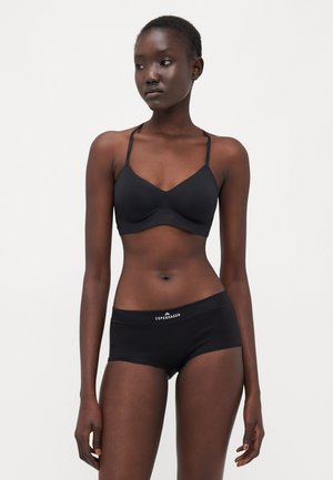 Reggiseno wireless nero con spalline sottile e design senza cuciture, abbinato a boxer neri con un logo bianco sulla vita.