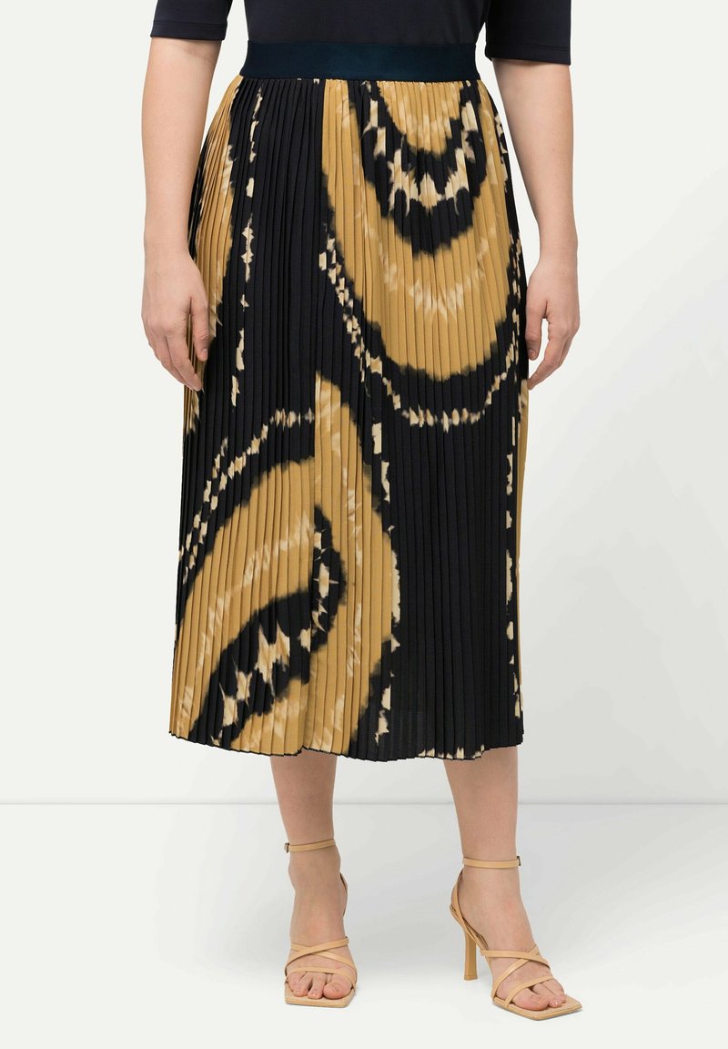 Plisserad midi-kjol med ett svart, beige och krämfärgat swirlmönster. Har en bred midjeresår. Stylad med snörskor i beige med hög klack.