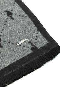 Szary wełniany szalik z czarnymi frędzlami, z wzorem sylwetek i kropkowanych linii. Zawiera srebrną metkę z dwoma otworami.