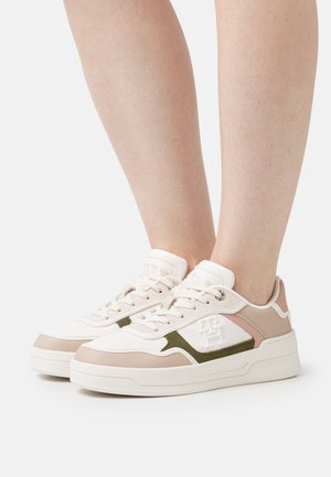 Zapatilla elegante con una combinación de cuero beige y rosa claro, acentos en verde oliva, panel lateral texturizado y una suela blanca gruesa.