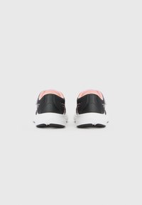 Baskets de sport noires avec des accents roses ; tige en mesh, col rembourré, semelle blanche et bande Velcro. Design simple axé sur le confort et le soutien.