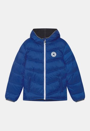 Veste matelassée bleue avec capuche, fermeture éclair blanche complète à l'avant, deux poches avant et un logo rond blanc Converse All Star sur la poitrine.
