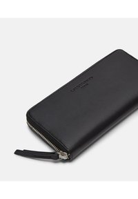 Czarny skórzany portfel o gładkiej fakturze, z zamkiem błyskawicznym i wytłoczonym logo. Charakteryzuje się eleganckim, prostokątnym kształtem bez widocznych przegródek.