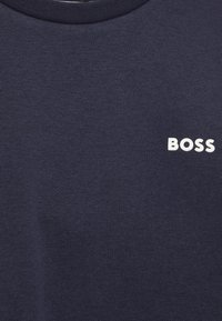 Tmavě modrá mikina s bílým logem "BOSS" na levé části hrudi. Tkanina má hladký, strukturovaný vzhled.