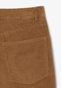 Tessuto di velluto a coste marrone con una texture a coste verticali. Tasche posteriori sinistre con logo ricamato. Design a vestibilità classica.