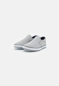 Szürke slip-on cipők textil felsőrésszel, fehér gumitalppal és rugalmas oldalsó panelekkel az egyszerű felhúzás érdekében. Minimalista dizájn sima textúrával.
