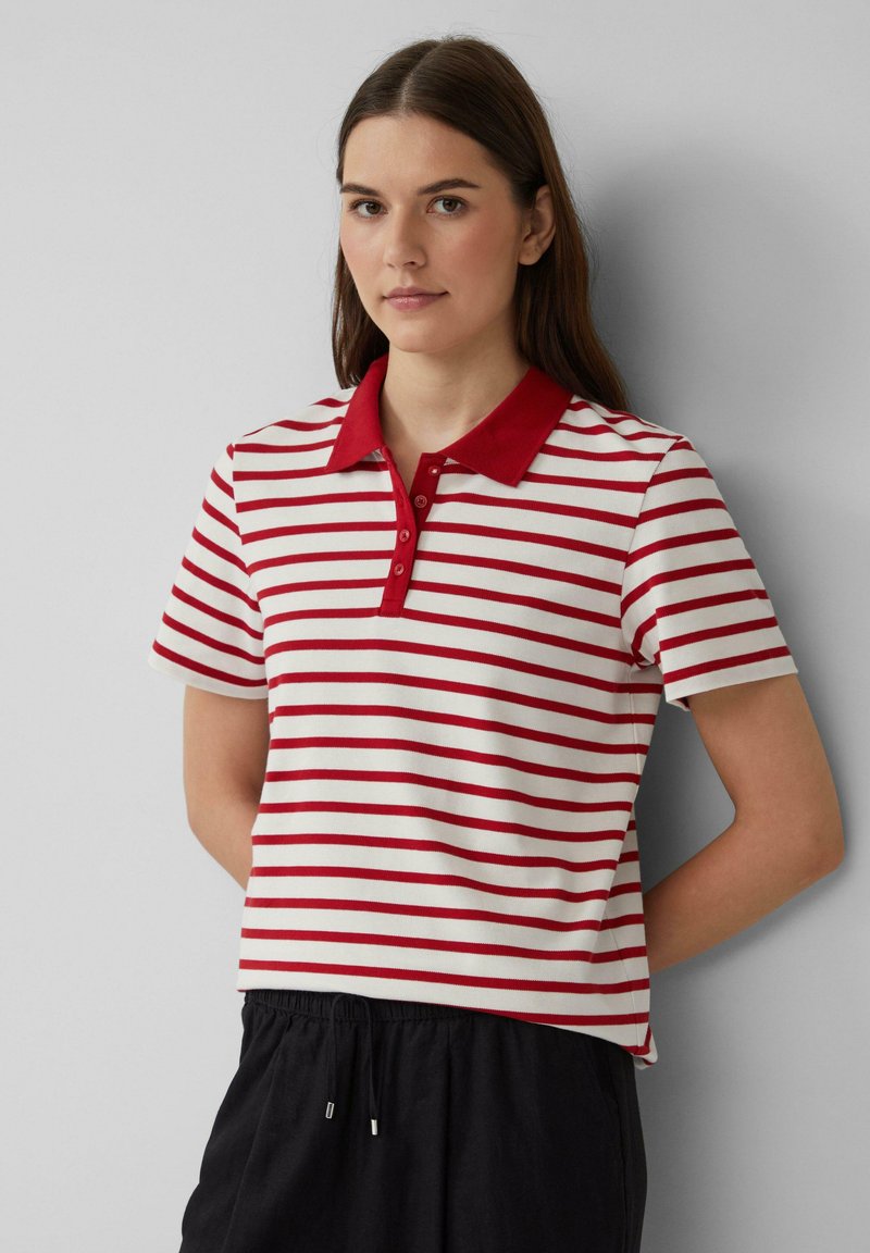 Rood en wit gestreepte polo met een effen rode kraag en een drieknoopsluiting. Het shirt heeft korte mouwen en is gemaakt van zachte stof.