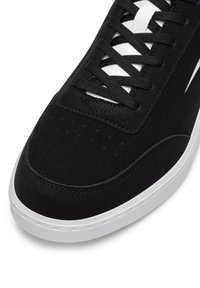 Adidași negri cu sireturi negre, talpă albă și detalii albe vizibile sub sireturi, pe un fundal alb.